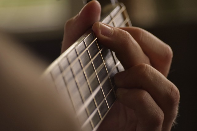 Eine Nahaufnahme der Hand einer Person, die auf die Saiten des Griffbretts einer Gitarre drückt und möglicherweise einen Akkord spielt. Der Hintergrund ist verschwommen, wodurch die Präzision der Finger auf den Saiten hervorgehoben wird – perfekt für einen Anfänger in einem Online-Gitarrenkurs.