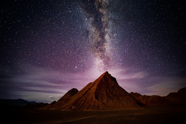 Ein majestätischer Berggipfel unter einem sternenklaren Nachthimmel, über dem die Milchstraße deutlich zu erkennen ist. Die an Astrokartografie erinnernde Szene ist mit verschiedenen Sternen gefüllt und schafft ein faszinierendes Schauspiel natürlicher Schönheit und kosmischer Wunder.